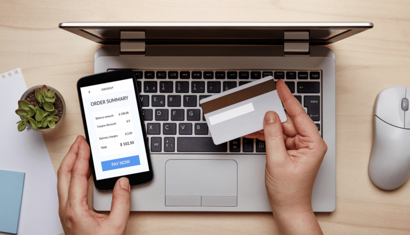 A woman using her credit card and phone to make an online e-commerce purchase.